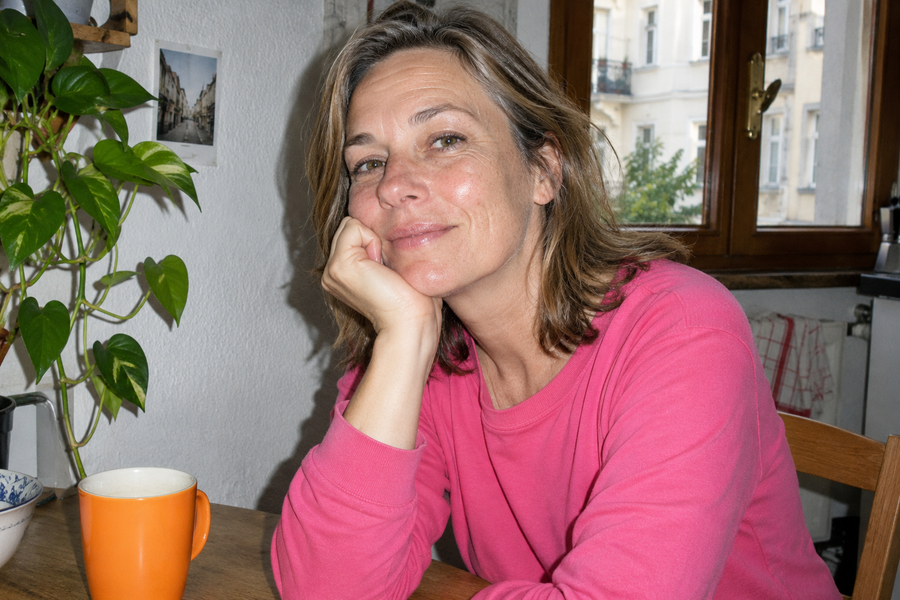 Frau im pinken Oberteil am Küchentisch.